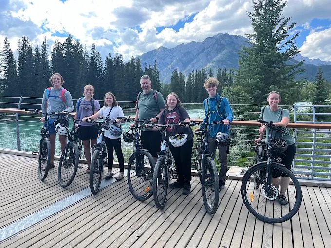 Group of riders on the Banff pedestrian bridge with Cascade Mountain behind